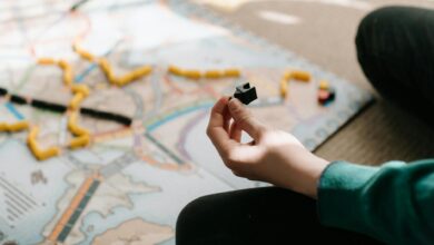 A person holding a game piece during a board game session indoors, showing strategy and leisure activity.