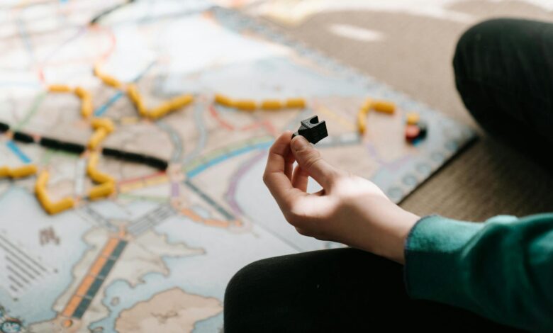 A person holding a game piece during a board game session indoors, showing strategy and leisure activity.