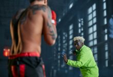 Intense indoor cosplay martial arts duel between two men in vibrant outfits.