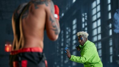 Intense indoor cosplay martial arts duel between two men in vibrant outfits.