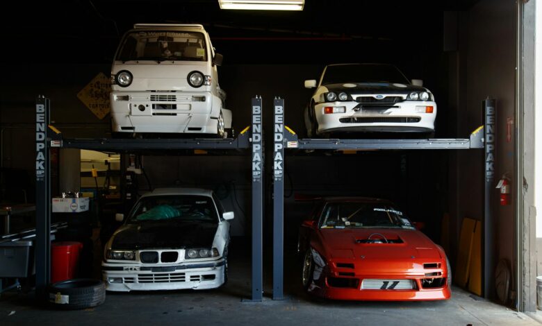 A collection of modified sports cars on a mechanical garage lift in Compton, CA.