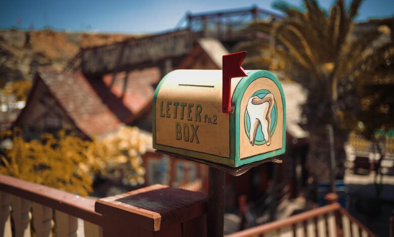A vintage mailbox with dental artwork in a sunny outdoor setting.