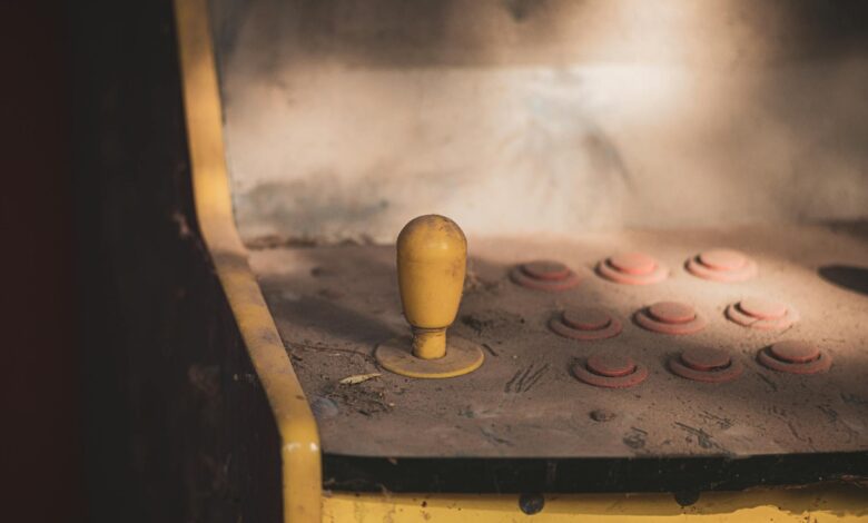 Close-up of a dusty vintage arcade machine control panel with joystick and buttons, evoking nostalgia.