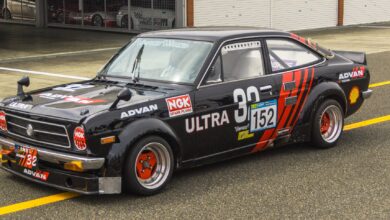 Classic black race car parked at the pit lane, showcasing retro design and vibrant graphics.