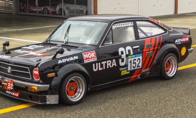 Classic black race car parked at the pit lane, showcasing retro design and vibrant graphics.