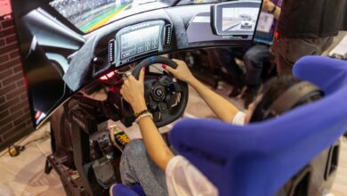 Person using a realistic VR racing simulator at a gaming event, focused on the immersive experience.