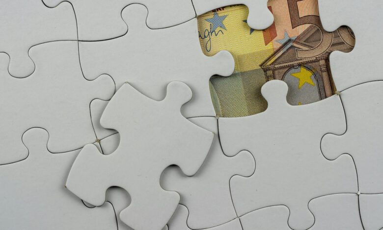 Close-up of a jigsaw puzzle missing piece revealing Euro currency underneath.