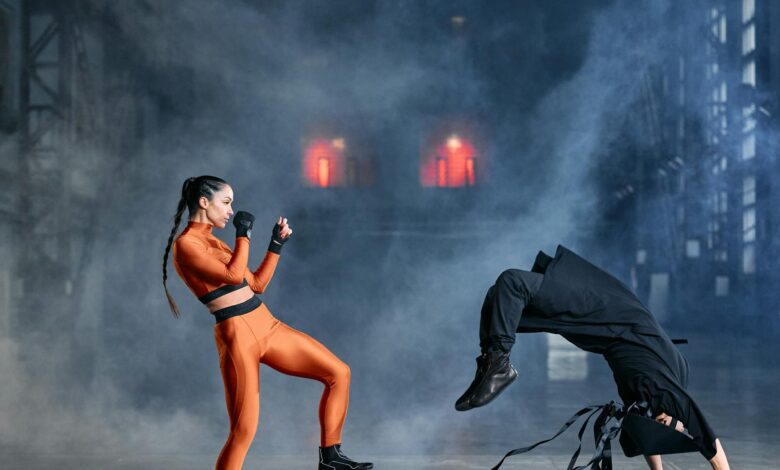 Two cosplayers in martial arts poses amidst smoke, embodying game characters in action.