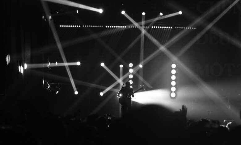 Captivating black and white image of a guitarist performing with dramatic lighting effects on stage.