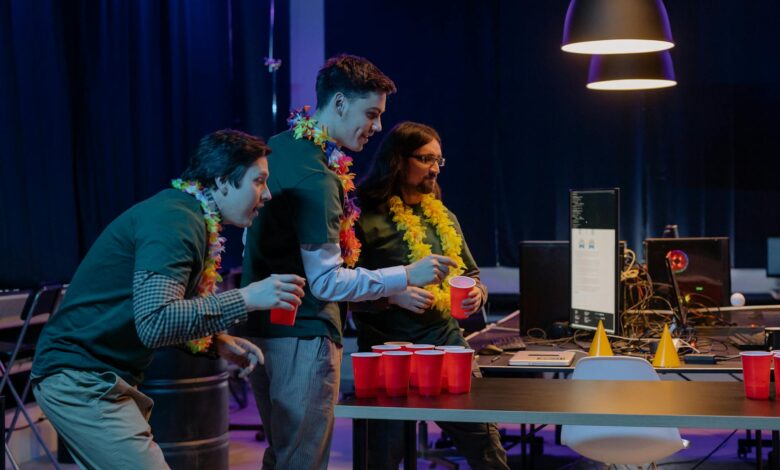 Group of male colleagues enjoying a fun beer pong game during an office party night.