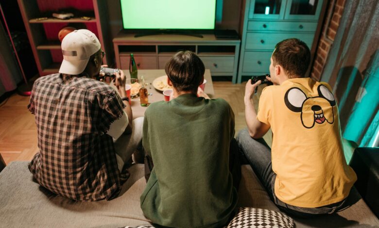 Three young men enjoying a home gaming session together, playing video games in a cozy indoors setting.
