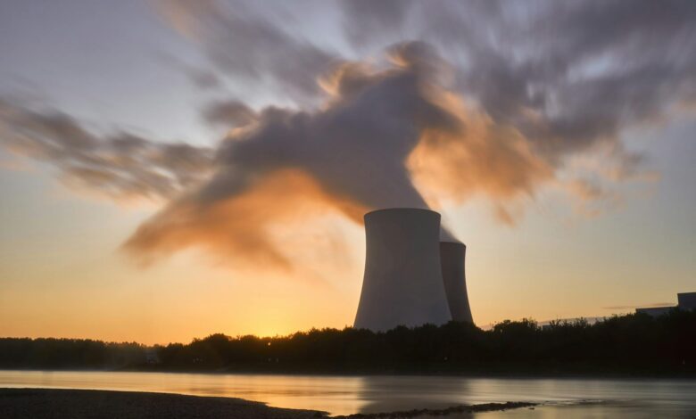 Dramatic image of a nuclear power plant at sunrise with steam rising into a colorful sky.