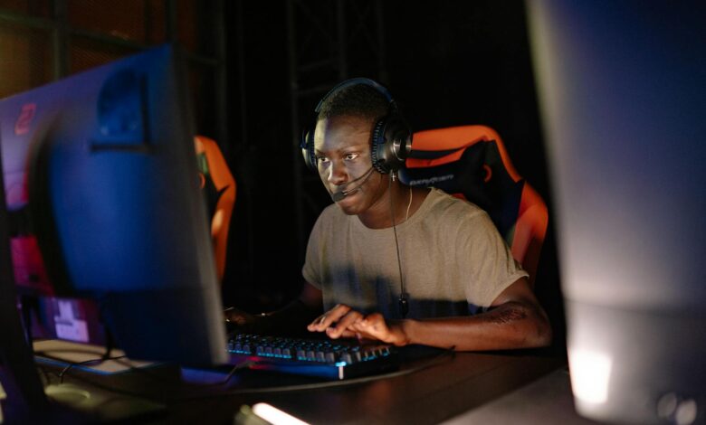 Young adult male intensely focused on computer gaming, using headset and gaming keyboard indoors.