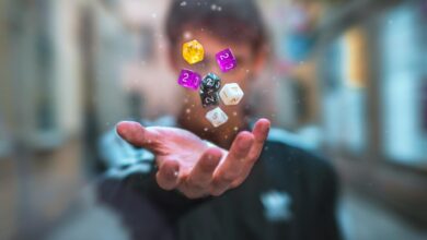 Colorful dice float above a hand with a blurred background, creating a dynamic and abstract visual.