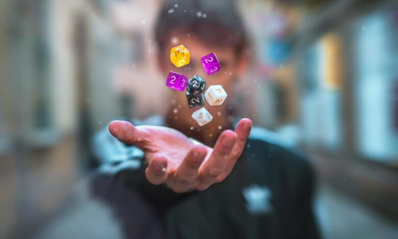 Colorful dice float above a hand with a blurred background, creating a dynamic and abstract visual.
