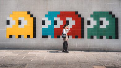 A woman walks past vibrant, pixelated video game art on a wall in Hong Kong, capturing a blend of urban life and pop culture.