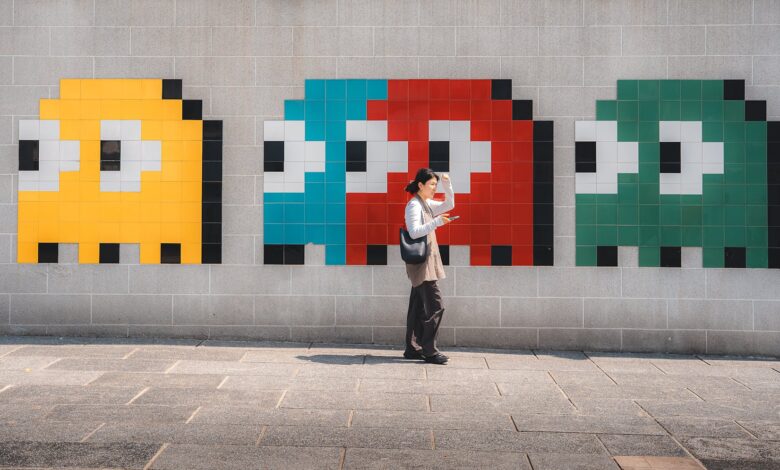 A woman walks past vibrant, pixelated video game art on a wall in Hong Kong, capturing a blend of urban life and pop culture.