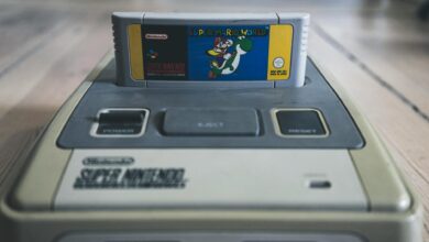 Vintage video game console with cassette with bright sticker on surface on wooden floor