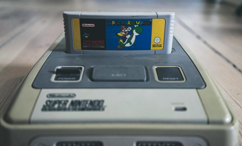 Vintage video game console with cassette with bright sticker on surface on wooden floor