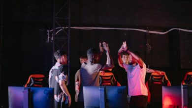 A diverse group of young gamers celebrating a victory with high-fives in a dark gaming room.