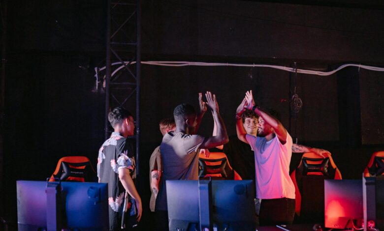 A diverse group of young gamers celebrating a victory with high-fives in a dark gaming room.