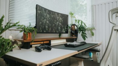 A stylish home office setup with a curved monitor, keyboard, and green plants.