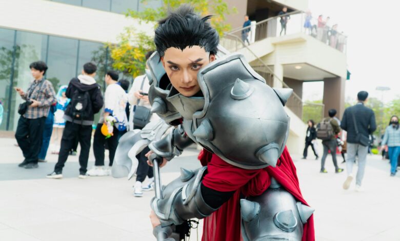 Man in intricate fantasy armor posing at a vibrant outdoor cosplay event.