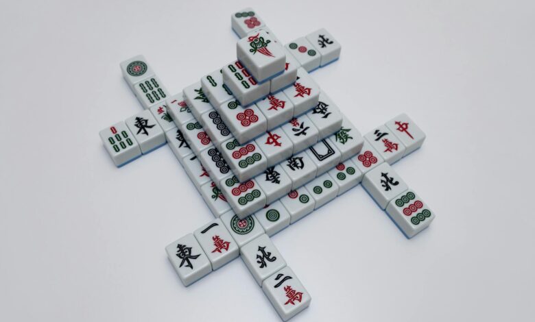 High-angle view of intricately arranged mahjong tiles on a white surface, showcasing traditional symbols.