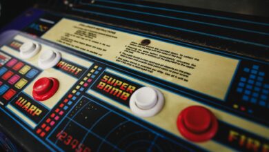 Close-up of a vintage arcade game control panel with colorful buttons and instructions.