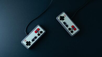 Top view of two retro gaming controllers on a minimalist dark background.