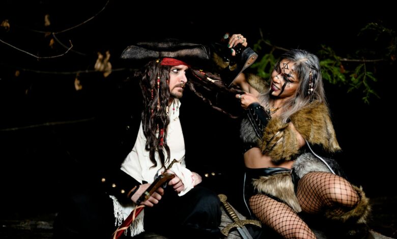 Two adults in pirate and warrior costumes pose at night for a Halloween themed photoshoot.