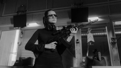 Woman at an indoor shooting range holding a sniper rifle.