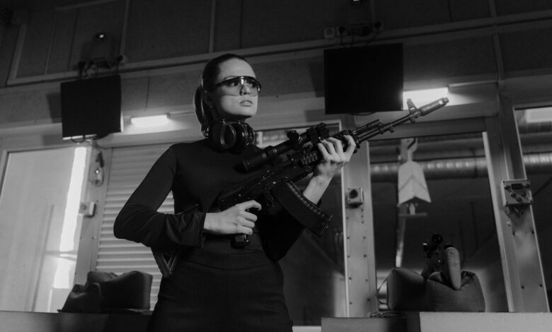 Woman at an indoor shooting range holding a sniper rifle.