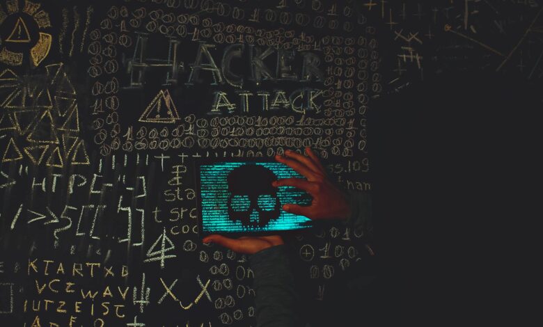 A hacker in a black hoodie using a tablet displaying a skull, surrounded by chalk symbols and 'Hacker Attack' text.