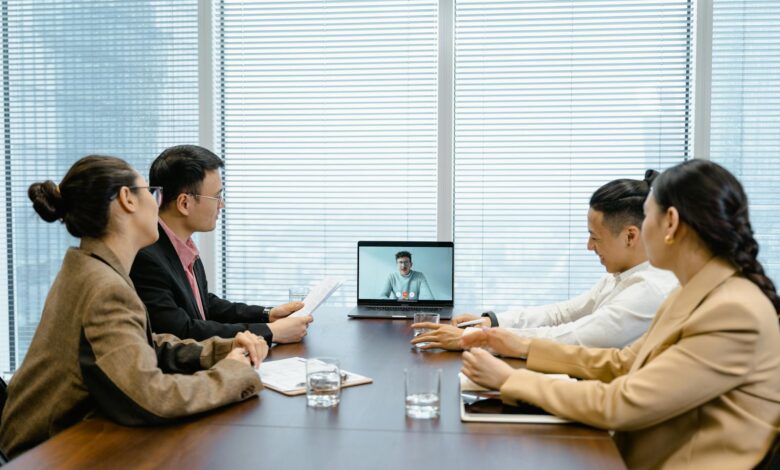 Business meeting with video call setup, highlighting teamwork and communication in a modern office environment.