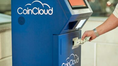 A person using a CoinCloud Bitcoin ATM to insert cash for cryptocurrency transactions.