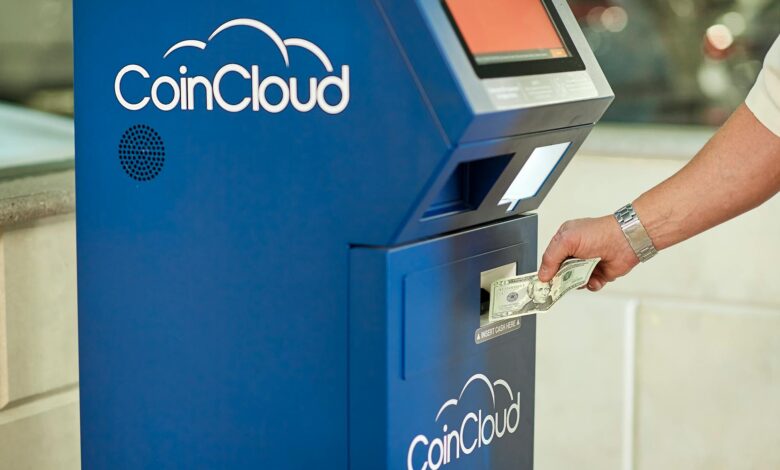 A person using a CoinCloud Bitcoin ATM to insert cash for cryptocurrency transactions.