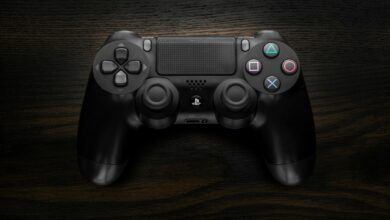 High-resolution image of a Sony DualShock 4 game controller against a dark wooden background.