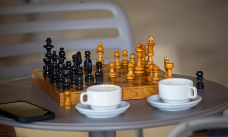 A chess board setup on a cafe table with two cups of coffee, ready for a casual game.