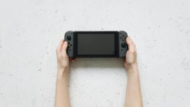 Top view of hands holding a portable gaming console against a textured white background.