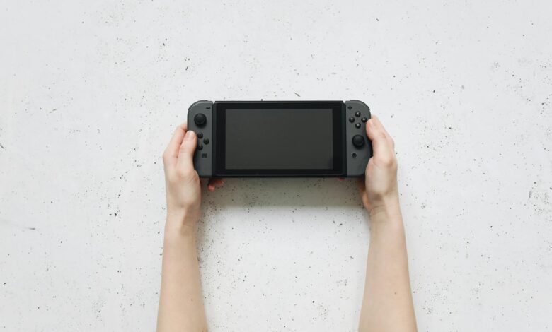 Top view of hands holding a portable gaming console against a textured white background.
