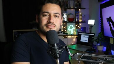 A podcaster in a home studio with neon lighting and tech equipment.