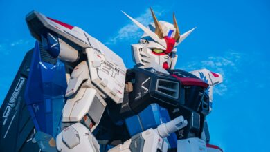Close-up of a giant Gundam robot statue set against a clear blue sky.