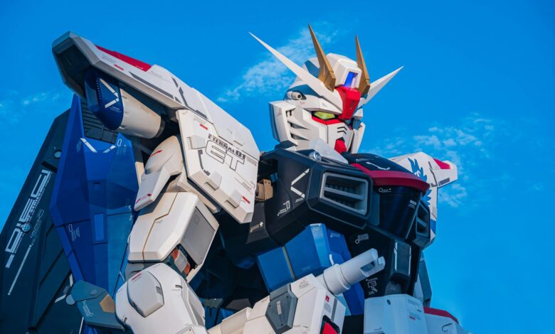 Close-up of a giant Gundam robot statue set against a clear blue sky.