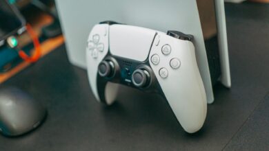 Close-up of a PlayStation 5 controller resting on its console, showcasing modern gaming technology.