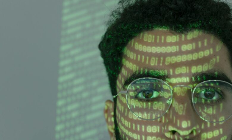 Close-up of a man with binary code projected on his face, symbolizing cybersecurity.