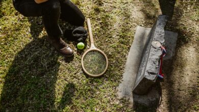 A solemn scene of a fallen tennis player memorialized with a racket and ball at a grave.
