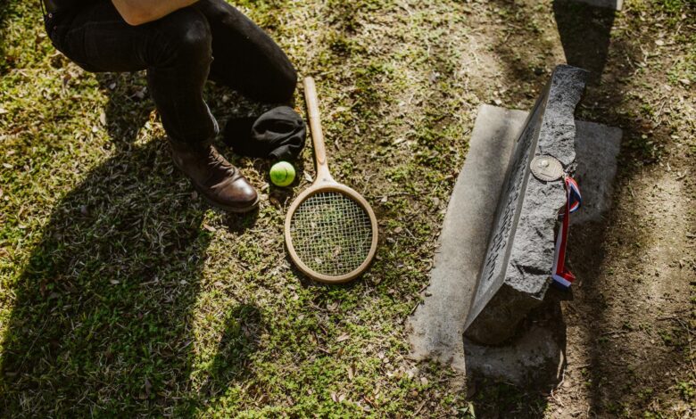 A solemn scene of a fallen tennis player memorialized with a racket and ball at a grave.