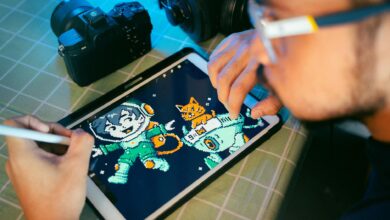 Person drawing digital art on a tablet using a stylus next to camera and headphones.