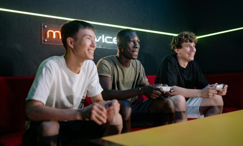 Three friends enjoy gaming together indoors, smiling and engaged with controllers.